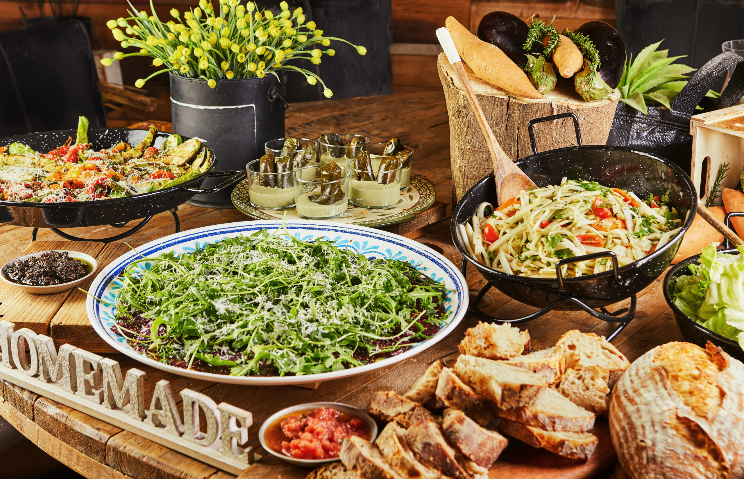 Buffet with a large selection of vegetable dishes and salads and Italian bread, healthy food